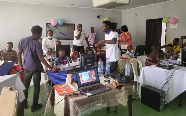 Children working on computers with IT4Africa volunteers at an MBCode workshop